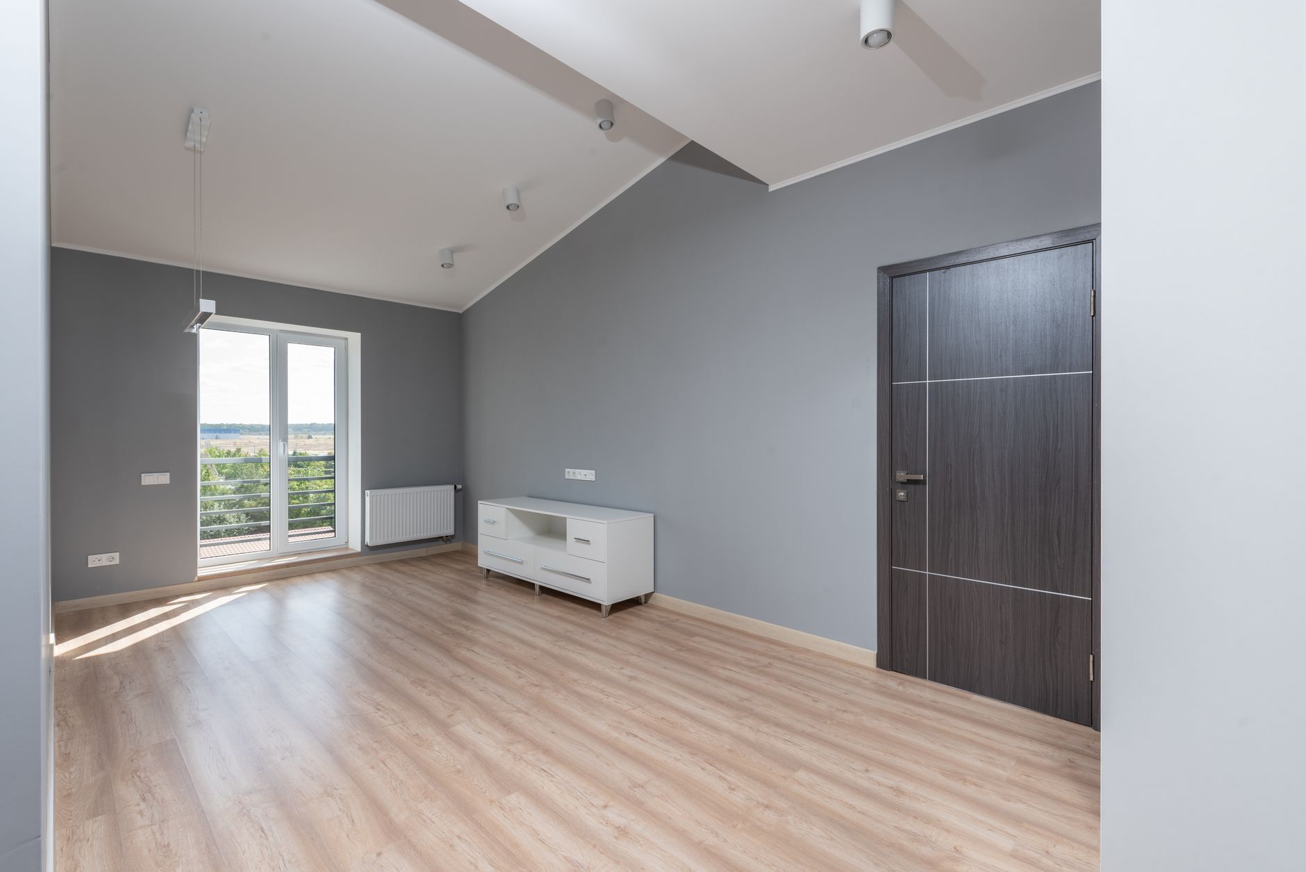 A bright empty modern room with hardwood floors and a large window